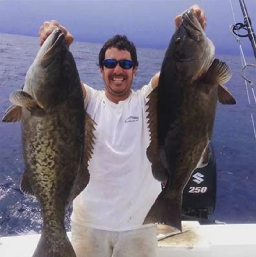 fisherman holding two grouper