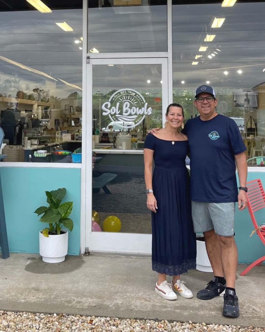Two people standing on a sidewalk in front of a business.