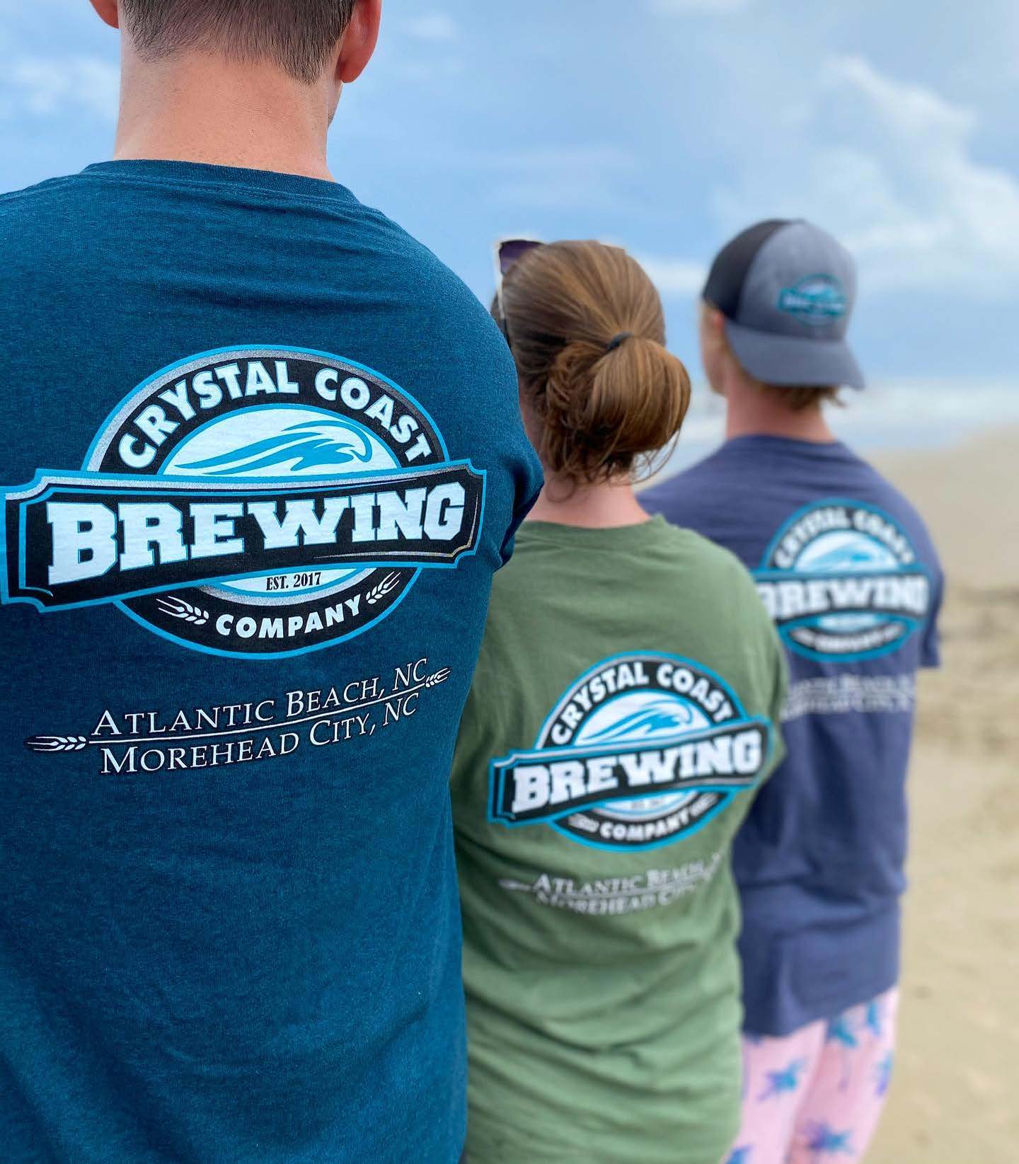Matt Poppe- Crystal Coast Brewing Company three people standing on the beach on a sunny day