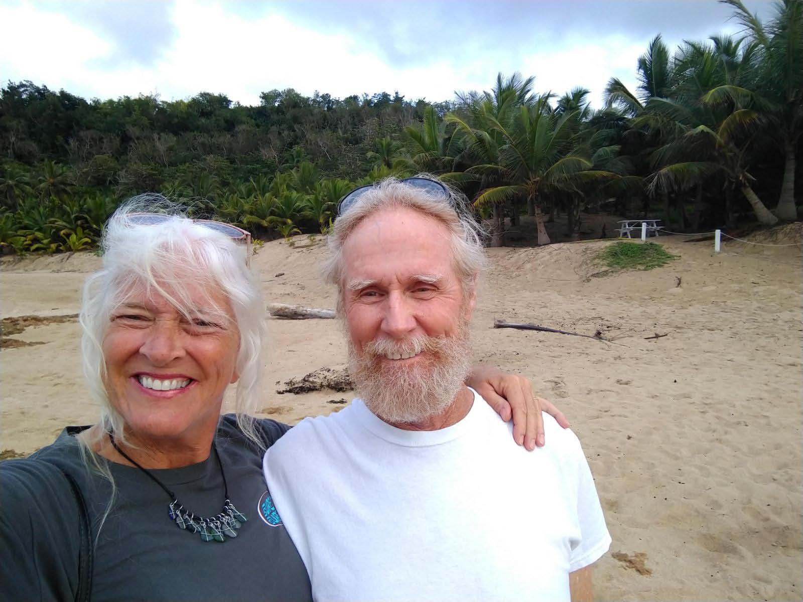 two people standing on a beach with cloud cover